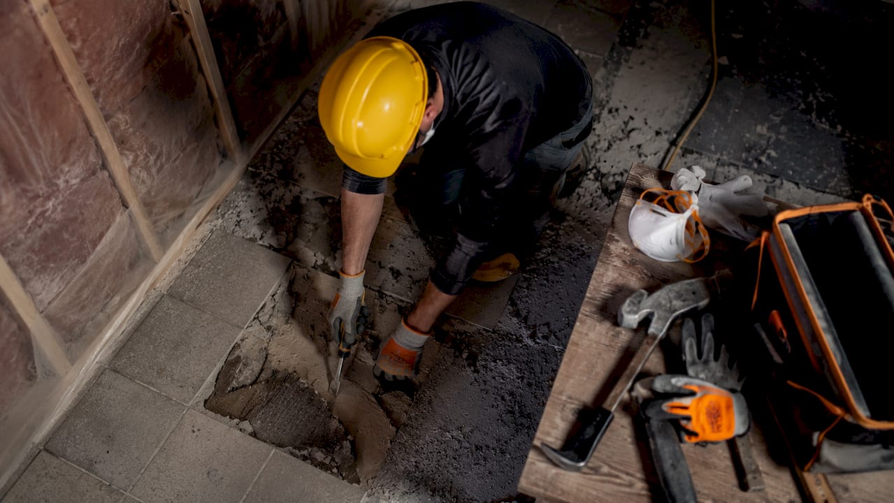 Construction worker removing hazardous floor tiles